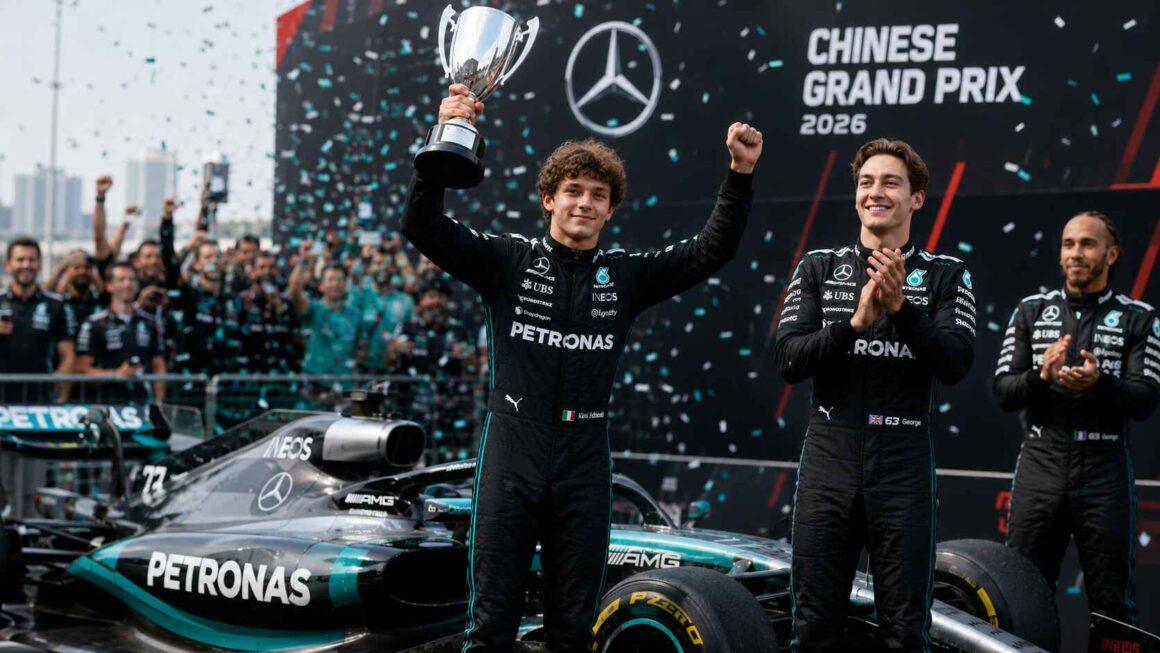 Trois pilotes en combinaisons noires Mercedes sur le podium du Grand Prix de Chine 2026. Un homme brandit un trophée.